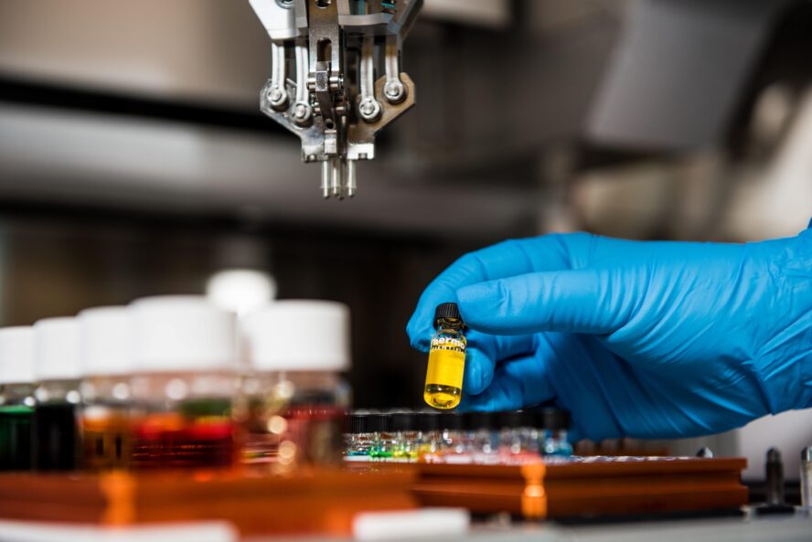 Lab technician in a laboratory loading a vial into a tray of vials reading for testing.