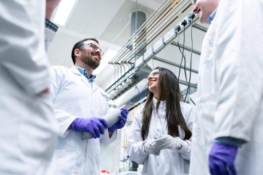 Group of three laboratory technicians in lab coats talking
